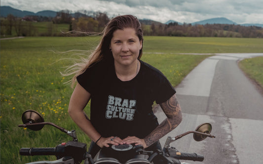 Femme Rider sitting on a motorcycle with black Brap Culture Club Tee
